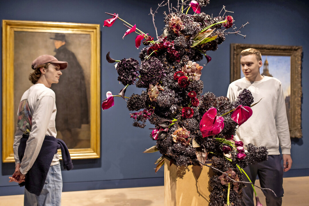 Wilhelm Schmurr: Bildnis Werner Heuser, 1902, floral interpretiert von Christina Janet Schacke, 
Blumenhaus am Hofgarten
: Gegen den Strom mit 
<i>Vanda</i>
, 
<i>Calla</i>
, 
<i>Scabiosa </i>
und Aubergine