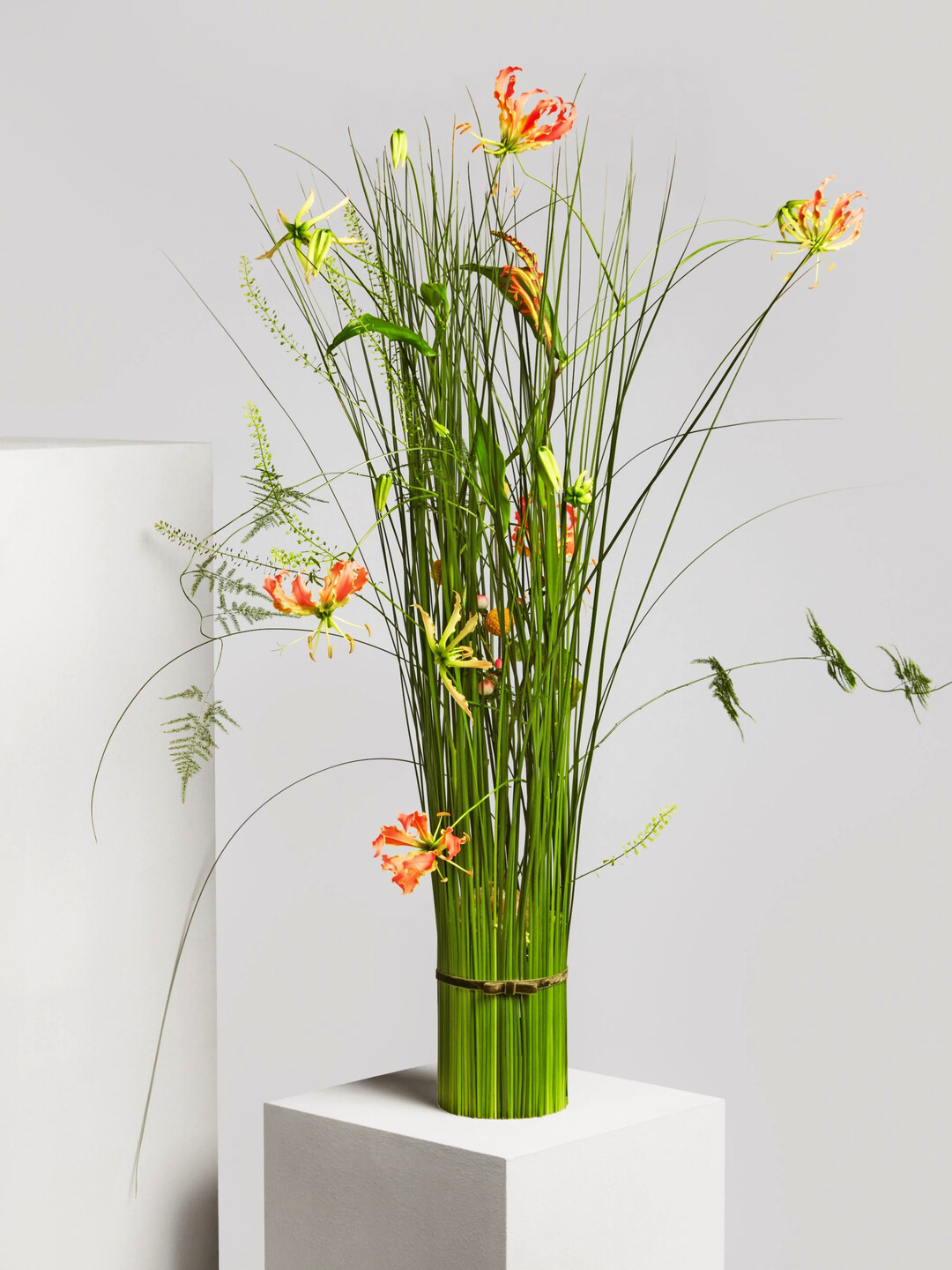"Dancing Orioles" ist ein formal-lineares Arrangement von beeindruckender Eleganz. In einer hohen zylindrischen Glasvase entfaltet sich eine lebendige Komposition aus ausgewhlten Blten und Blttern, die Dynamik und Harmonie perfekt miteinander verbindet. Die Basis bilden apricotfarbene Eustoma. Darber tanzen orangefarbene Gloriosa und Montbretien, sonnige Craspedia, rosa Hypericum sowie Thlapsi und Philodendron - locker und versetzt gesteckt fr eine moderne, grafische Linienfhrung. (Preis: 127,95 Euro)