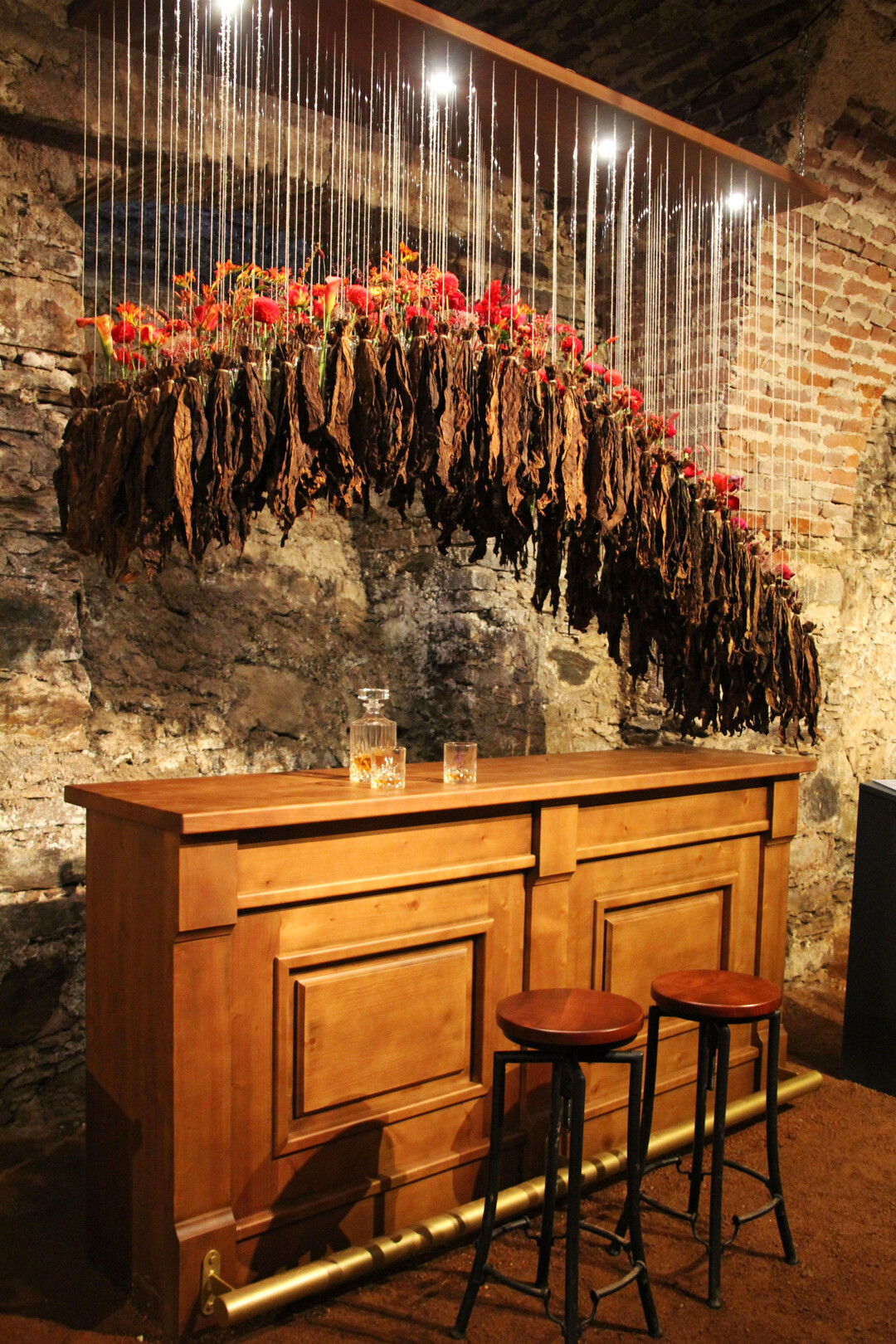 Der Themengestaltung Ulme von 
<b>Barbara Schildendorfer</b>
 lag ein Gesprch mit der Great Elm im Central Park/New York zugrunde. In meiner Arbeit setze ich mich mit einer der dunkelsten Phasen der US-amerikanischen Geschichte auseinander: dem Brgerkrieg zwischen den Nord- und Sdstaaten, der vor allem durch die Sklaverei geprgt war. Sie schuf ein florales Kunstwerk, das ber einer Bar eine mit Blumen gefllte geschwungene Form von Glasgefen und gebndelten Tabakblttern zeigte. Die Glser enthielten rote Rosen, 
<i>Nigella</i>
, Knterichsorten, Astilben, dunkelrote 
<i>Helleborus </i>
u.v.m. Die Auswahl der Farben war dabei entscheidend. Rot steht fr den Krieg und das unendlich viele Blut, das vergossen wurde. Die wechselnde Farbqualitt beschreibt die unterschiedlichen Phasen des Krieges.