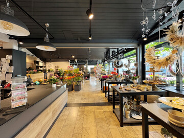 Der Verkaufsraum erhielt durch den Umbau eine neue Großzügigkeit und mehr Klarheit. Die dunkle Decke in Anthrazit streckt den Raum optisch in Länge und Breite, während die hellen Wände und die natürlichen Materialien Wärme und eine einladende Atmosphäre schaffen.