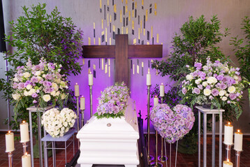 Weitere Trauerspenden erg�nzen den Sargschmuck, ohne mit ihm zu konkurrieren, und schaffen einen klaren, harmonischen Rahmen. Die Kombination aus Violett und Wei� (W�rde und Licht) � ein Farbdialog, der dem Moment des Abschieds eine sanfte Balance gibt. 