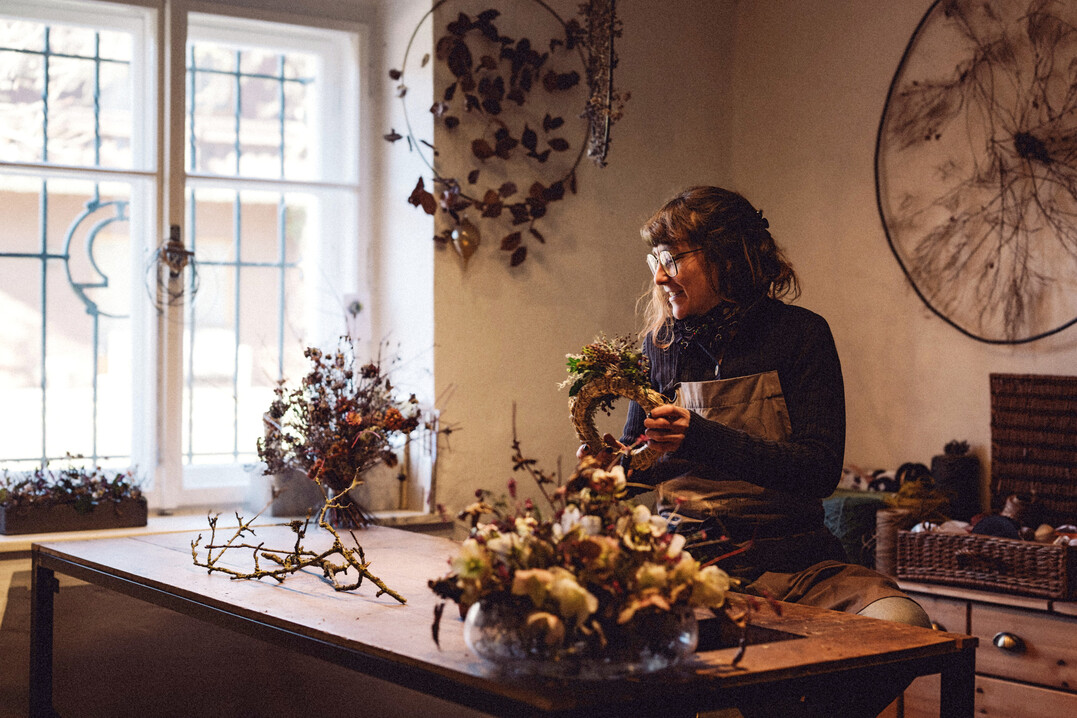 Zwischen alten Mauern und frischem Gr�n: Lisa Hartleitner arbeitet an einem ihrer charakteristischen, wild gebundenen Kr�nze. Die Floristin verarbeitet regionales Pflanzenmaterial zu nachhaltigen, lebendig wirkenden Werkst�cken.