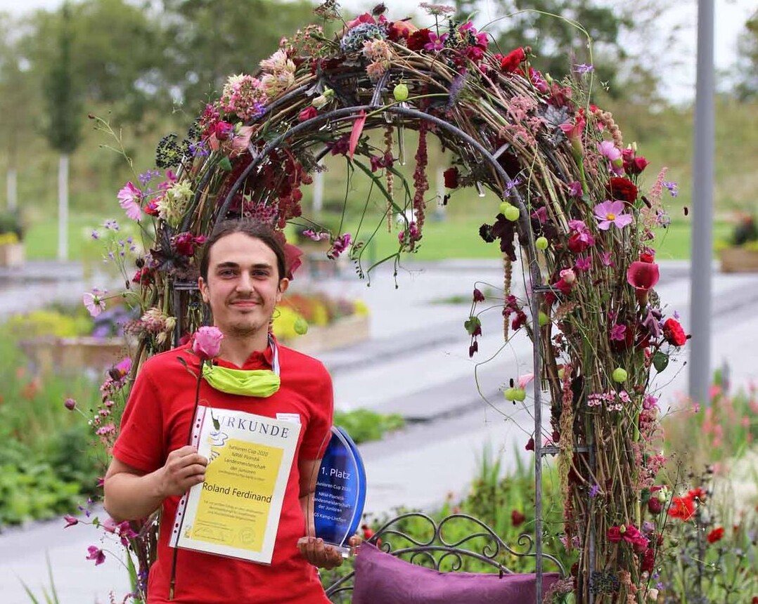 Roland Ferdinand, NRW-Floristik-Landesmeister der Junioren 2020, vor seinem floral gestalteten Bilderrahmen.