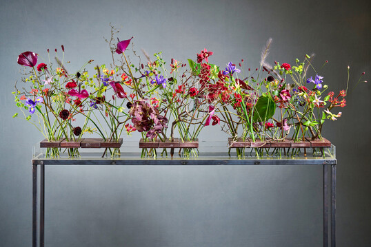 Like the ‘She blooms’ initiative, Elisabeth Schoenemann’s piece consists of three parts that support one another, thereby combining their dynamic energy. As an alternative to floral wire, the florist has drilled multiple holes through heavy clinker bricks.