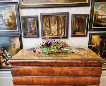 2) Im Gemldezimmer schmckt ein flaches Gesteck die Kommode, ohne den Blick auf die Bilder zu stren. Die Farbstimmung der Gemlde und Rahmen wird mit dunklen Floralien aufgegriffen, gelbe Blumen setzen Lichtpunkte.