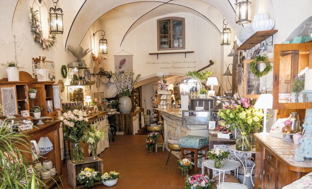 2) Regale, Schrnke, Sideboards stehen an den Wnden, alle dekoriert mit Geschirr, Lampen, Seifen, Schmuck, Schokoladen, Lesebrillen, aber natrlich auch vielen Blumenarrangements, die ber die Flche verteilt sind: mal als fertige Auftrge, die auf ihre Kunden warten, mal als kreative Idee, spielerisch leicht und wahre Hingucker.