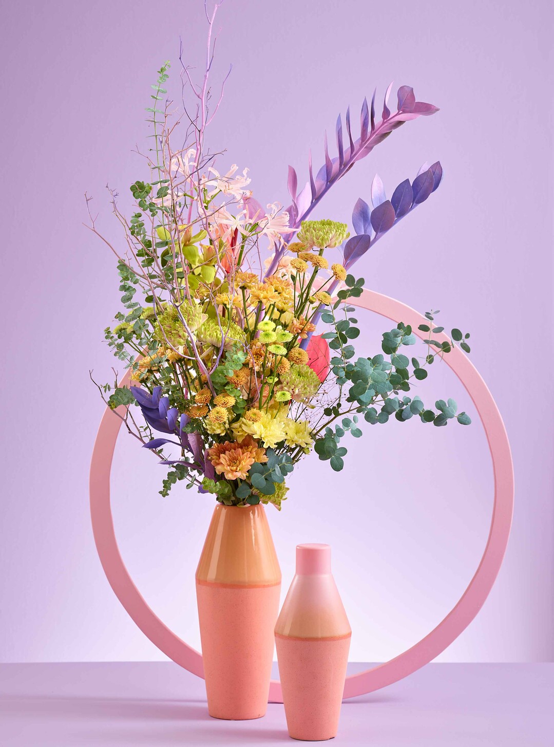 Reanimated Real: Hochgebundener Strau im Korean style. Violette Farb-Variationen, eine Ttenform, der Kreis und die ausbrechenden Zamioculcas (Glcksfedern) sind typische Vertreter dieses Trends. Spannung durch Form und Harmonie durch Farbe.