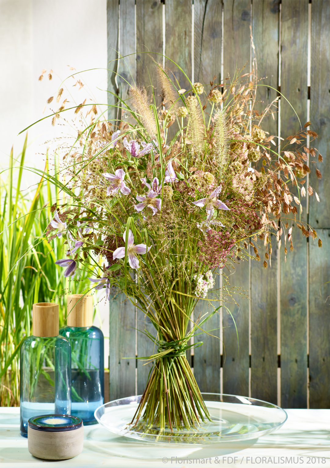 "Hudson Heaven", Feel the nature - Natur-Strau mit Wildgrsern: Der sommerliche Strau ist ungeknstelt und wirkt wie selbst gepflckt. Die natrliche Wirkung wird durch schwingende Grser und florales Beiwerk erzielt. Clematis-Blte setzen reizvollen Farbakzente.