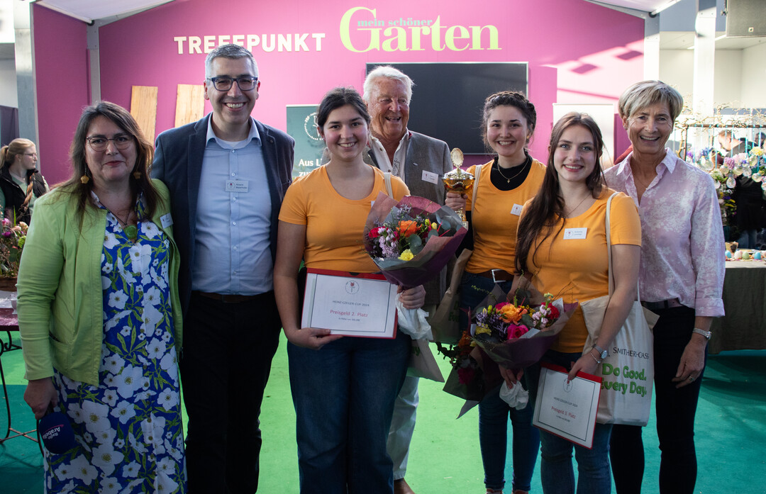Die drei Erstplatzierten beim Heinz-Czeiler-Cup 2024: Den Pokal holte die Gewinnerin Paula Eicher von Schön Floristik (3.v.r.). Silber ging an Marie Schäfer (3.v.l.) und Bronze an Antonia Limmer (2.v.r.).