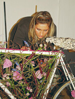 Die Floristen sollten ein Fahrrad dekorieren und anschließend noch
eine Runde damit drehen. Vanessa Schäfer, Köln, befestigte die Dekoration
am Rahmen und dekorierte den Sattel mit Flechten. Eva Latsch ließ
den Lenker weiß und entwickelte Floristik im hinteren Bereich und darüber
hinaus, so als ob hier der entstehende Fahrtwind sichtbar wird.